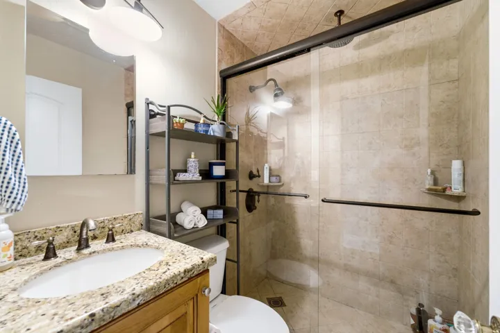 Glass-enclosed shower with a rainfall showerhead, tiled walls, and a built-in corner shelf