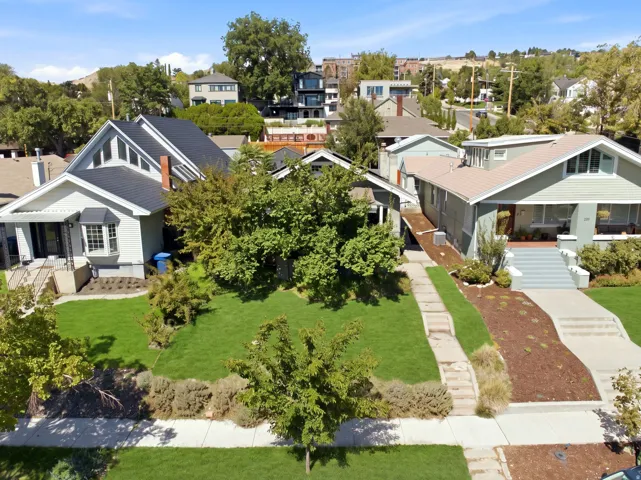 Well-manicured front lawn with mature trees and established landscaping