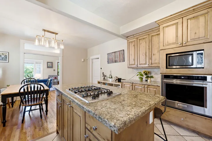 Kitchen featuring a center island with a gas cooktop, granite countertops, wood cabinetry, and stainless steel built-in appliances