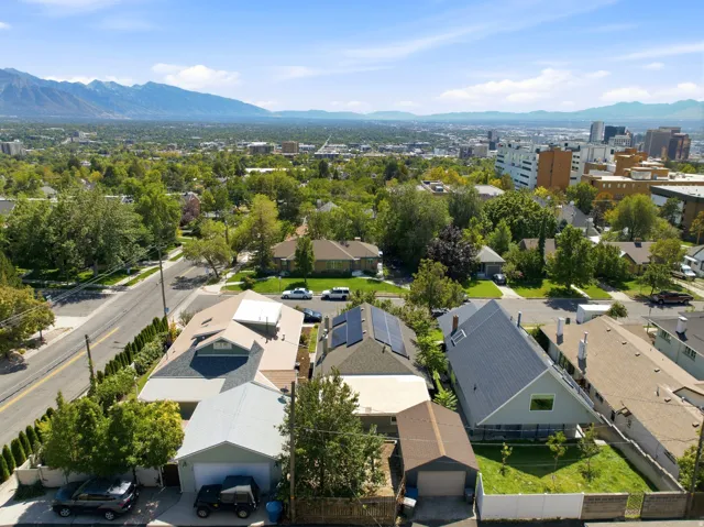 Solar panels visible on multiple rooflines, with a backdrop of a distant mountain range and urban skyline