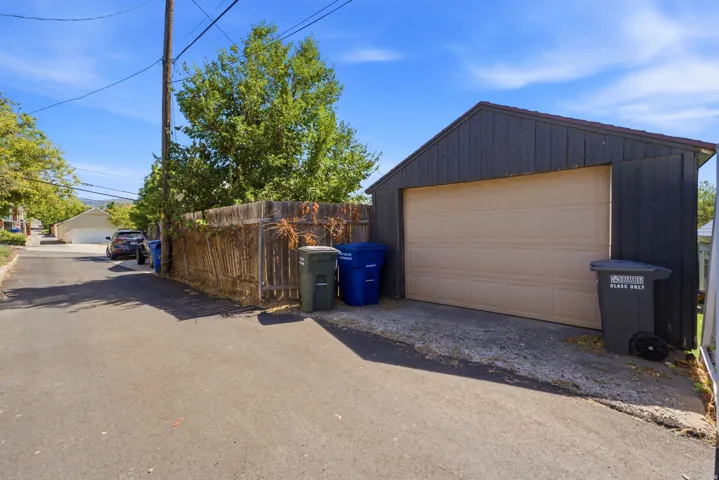 Detached garage with a paneled door, dark vertical siding, and a sloped roof