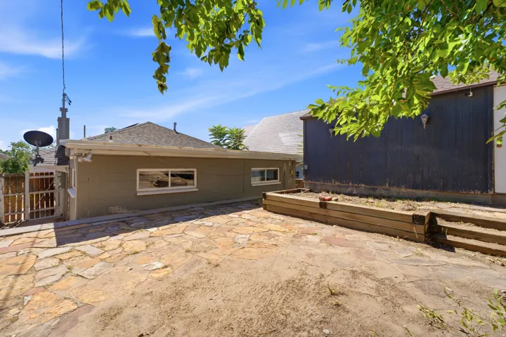 Stone patio featuring an elevated garden bed with wood retaining walls