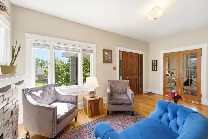Hardwood flooring, painted brick fireplace, a wood entry door, and double French doors