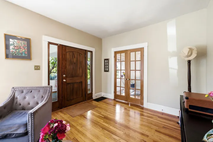 Hardwood flooring, natural wood entry door with sidelights, and natural wood French doors with glass panes