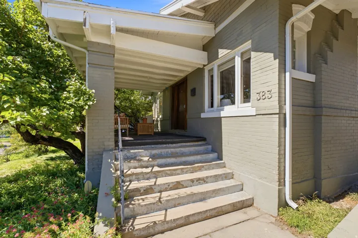 Brick exterior with white trim, covered front porch, and concrete steps