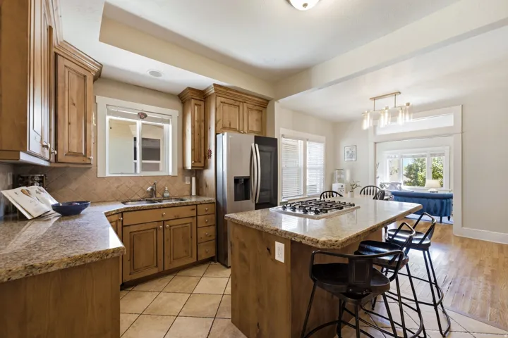 Kitchen featuring wood-finish cabinetry, granite countertops, stainless steel appliances, and tile flooring