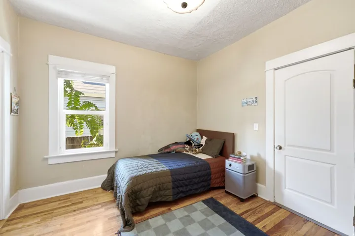 Hardwood flooring, painted walls, white trim, and a paneled door with an arched top
