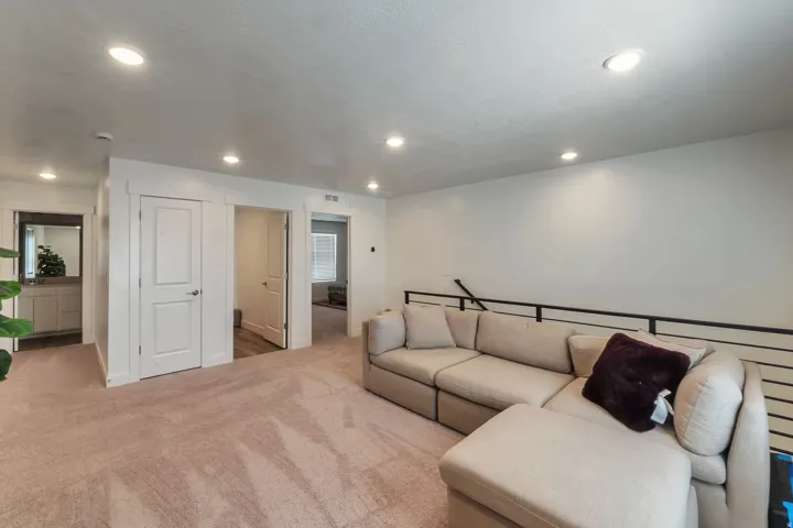 Recessed ceiling lighting, light-toned wall finishes, light-toned carpeting, black metal railing
