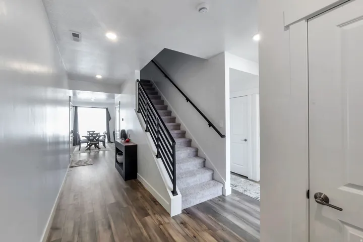 Wood-finish flooring, recessed lighting, carpeted staircase, and modern horizontal metal stair railing