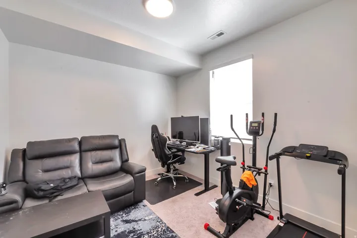 Recessed lighting illuminates this room with light-toned walls and carpeting