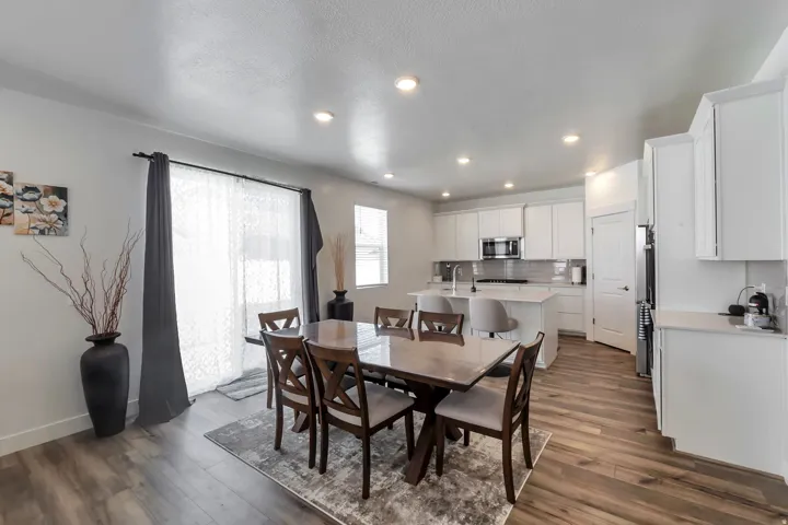 Open concept living area with wood-finish flooring, recessed lighting, white cabinetry, a kitchen island, and stainless steel appliances