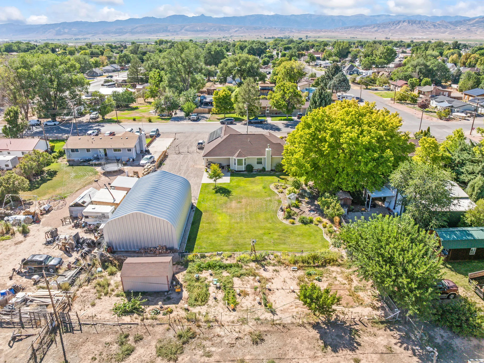 Expansive property featuring a large quonset hut, a manicured lawn, established landscaping, and a garden area