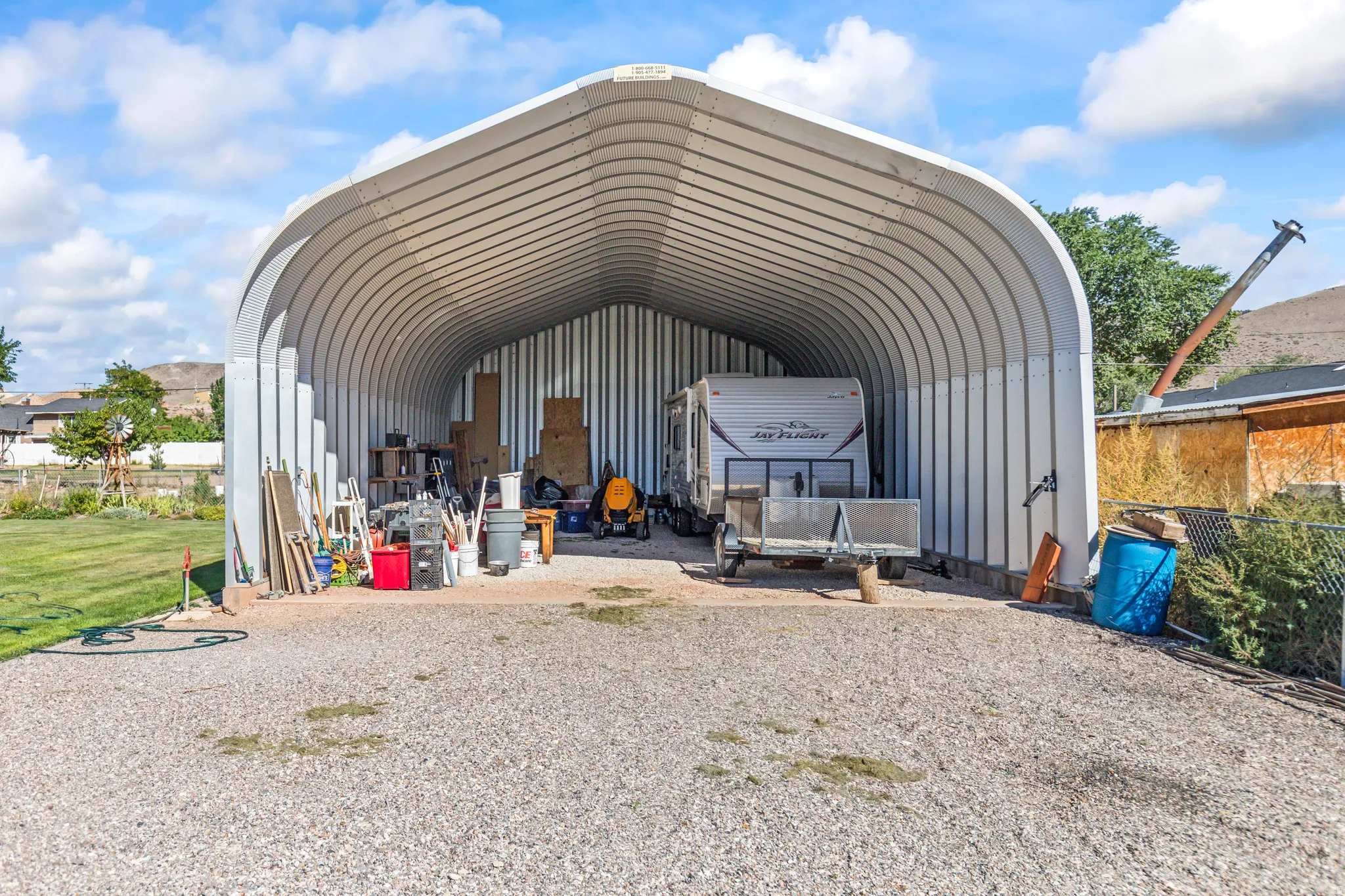 Quonset hut style structure with a corrugated metal roof and side panels, featuring a gravel floor