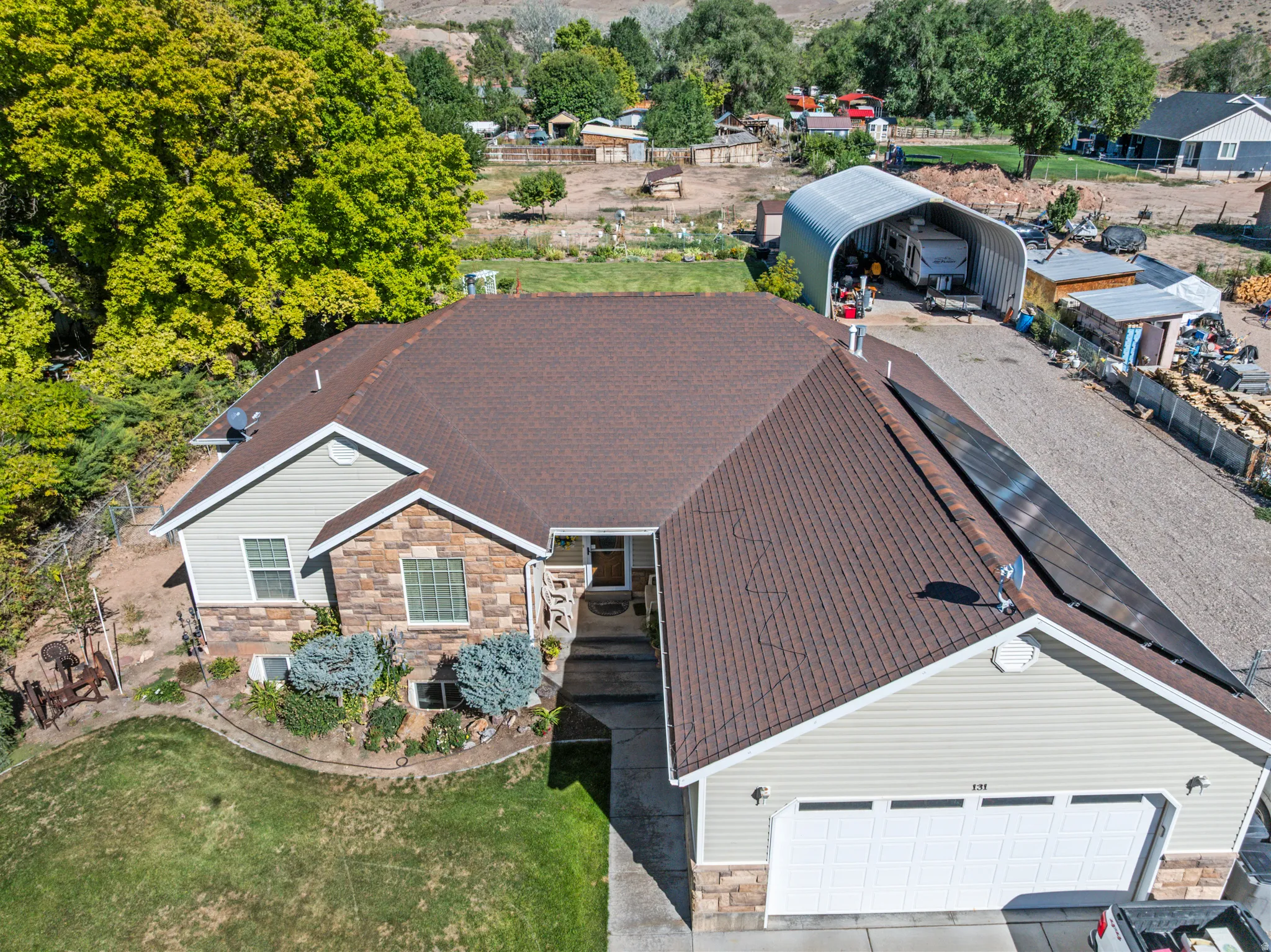 Stone facade home with an attached garage, landscaped front yard, and solar panels
