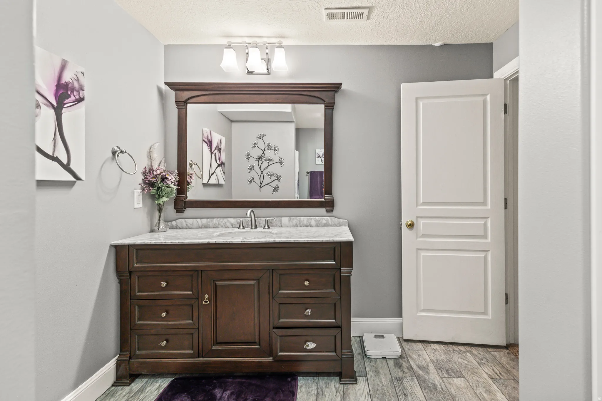 Dark wood-finish vanity with ample storage, integrated sink, and stone countertop