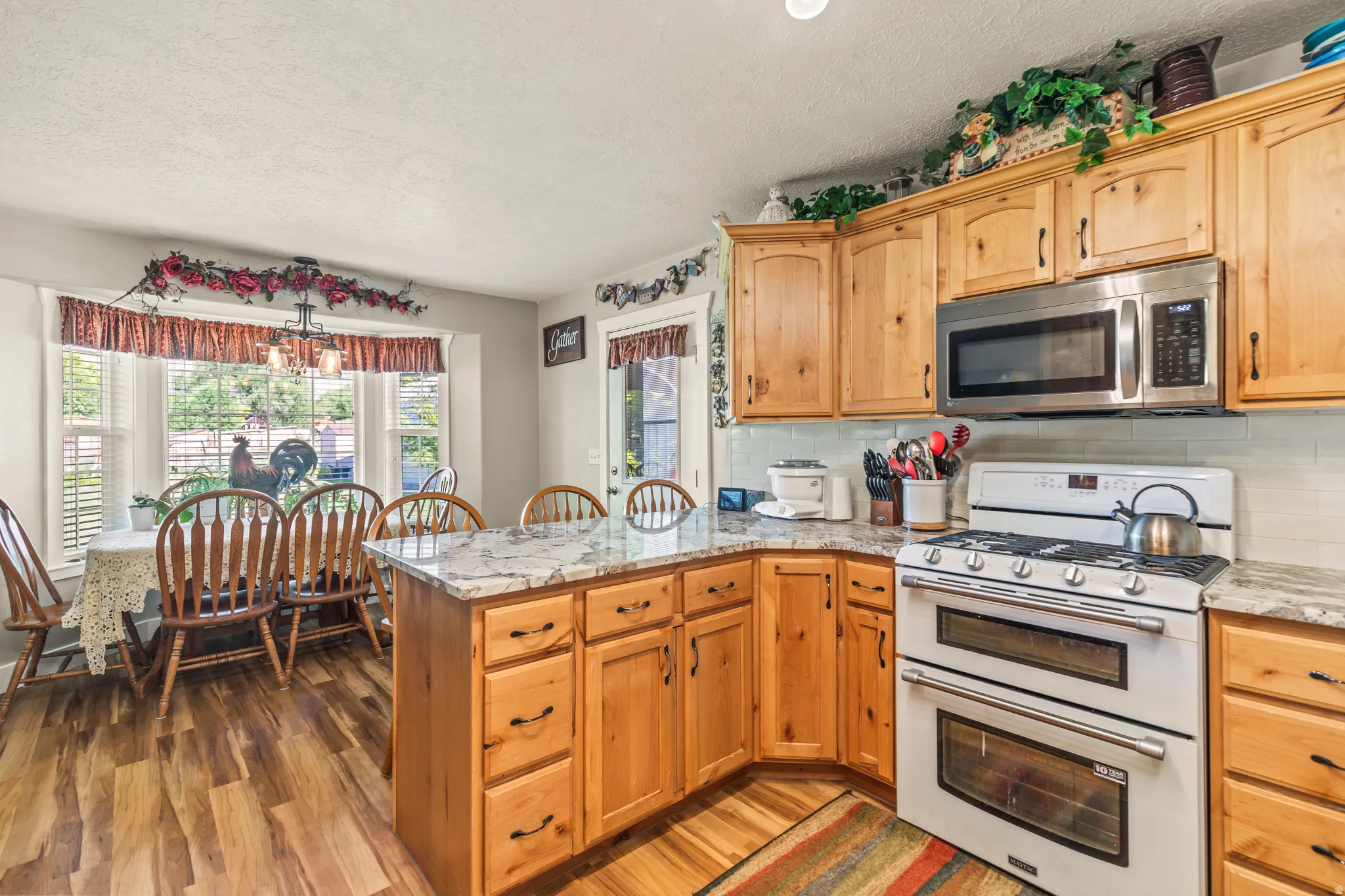 Kitchen featuring wood-finish flooring, light wood cabinetry, white subway tile backsplash, and light-toned countertops