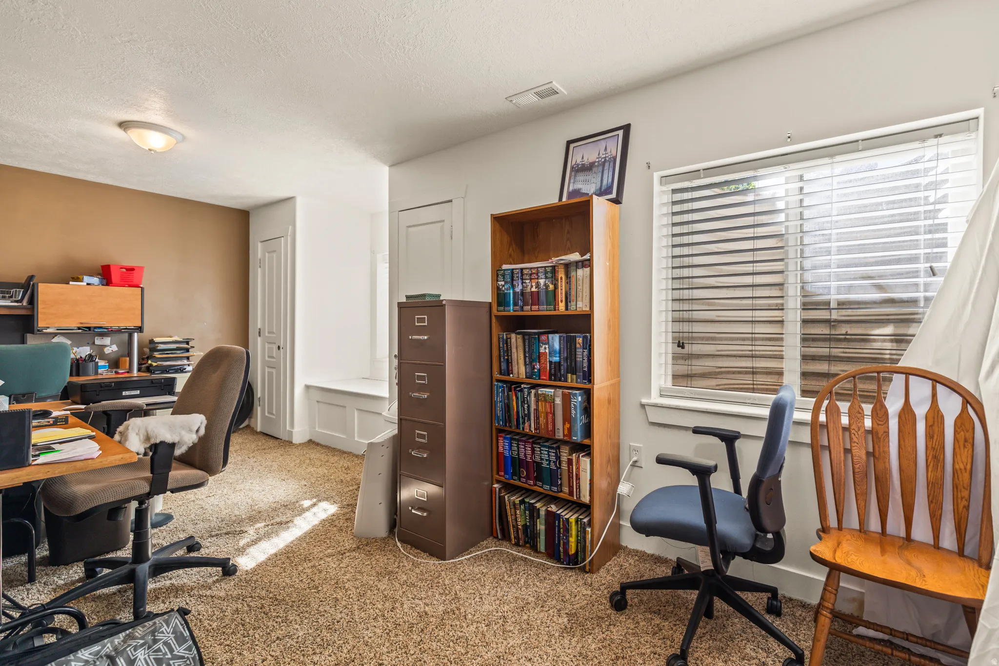 Carpeted flooring, window with blinds, built-in shelving, white trim, and a white interior door