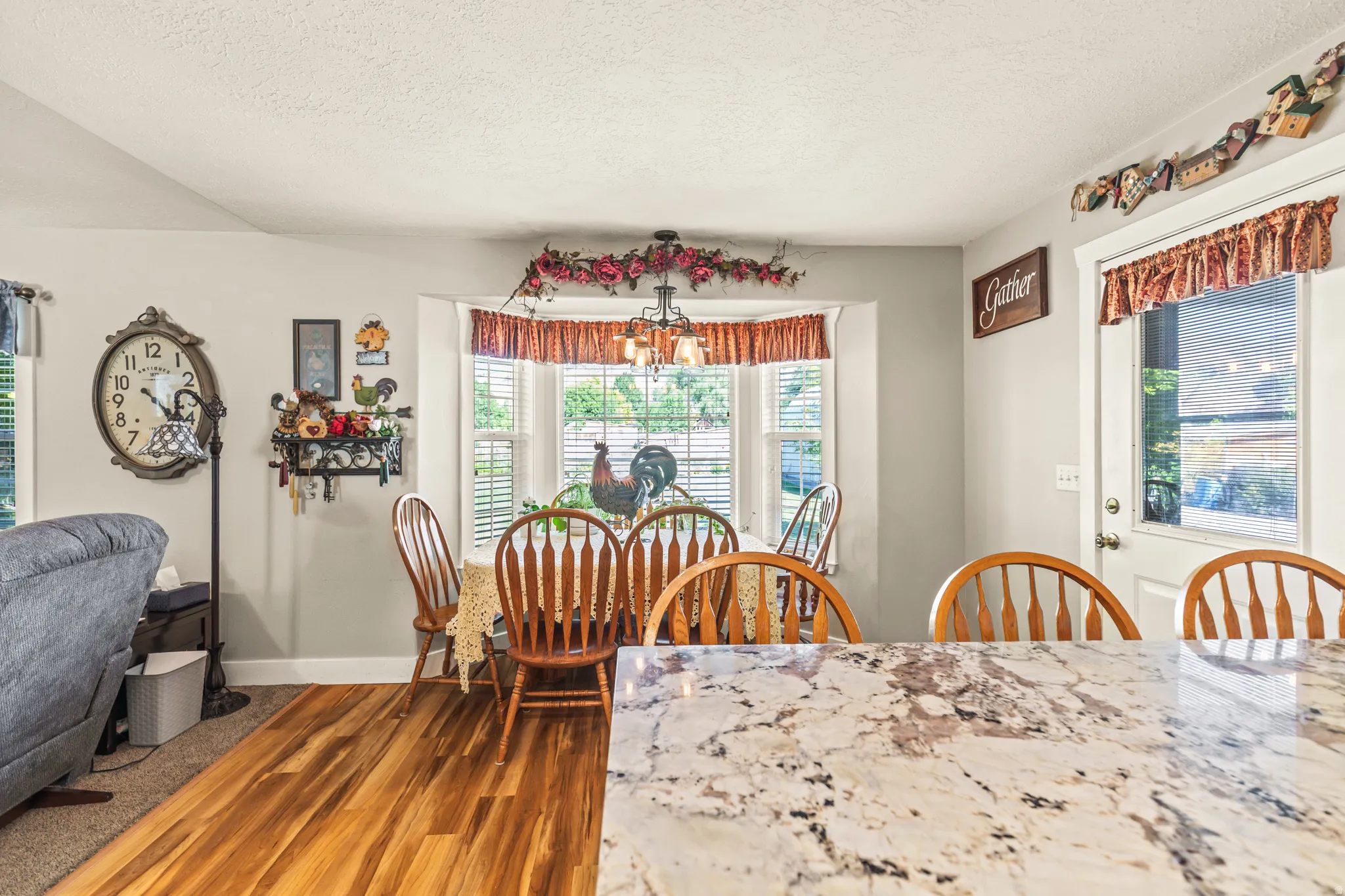 Granite-finish countertop, wood-finish flooring, bay window with louvered blinds, and a white paneled door