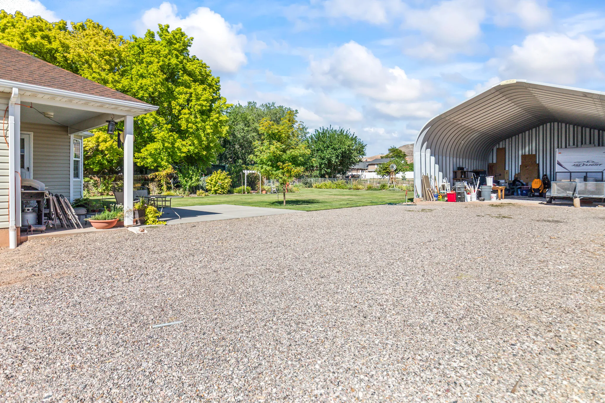 Expansive gravel driveway with a detached metal quonset hut structure