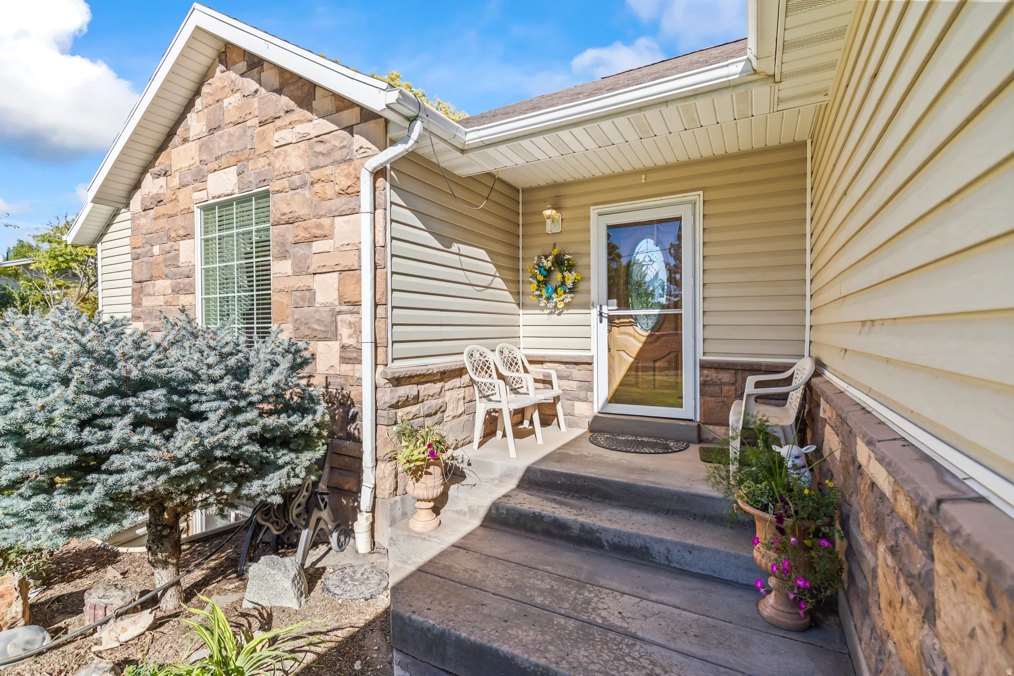 Stone facade accents, vinyl siding, and a covered porch entry