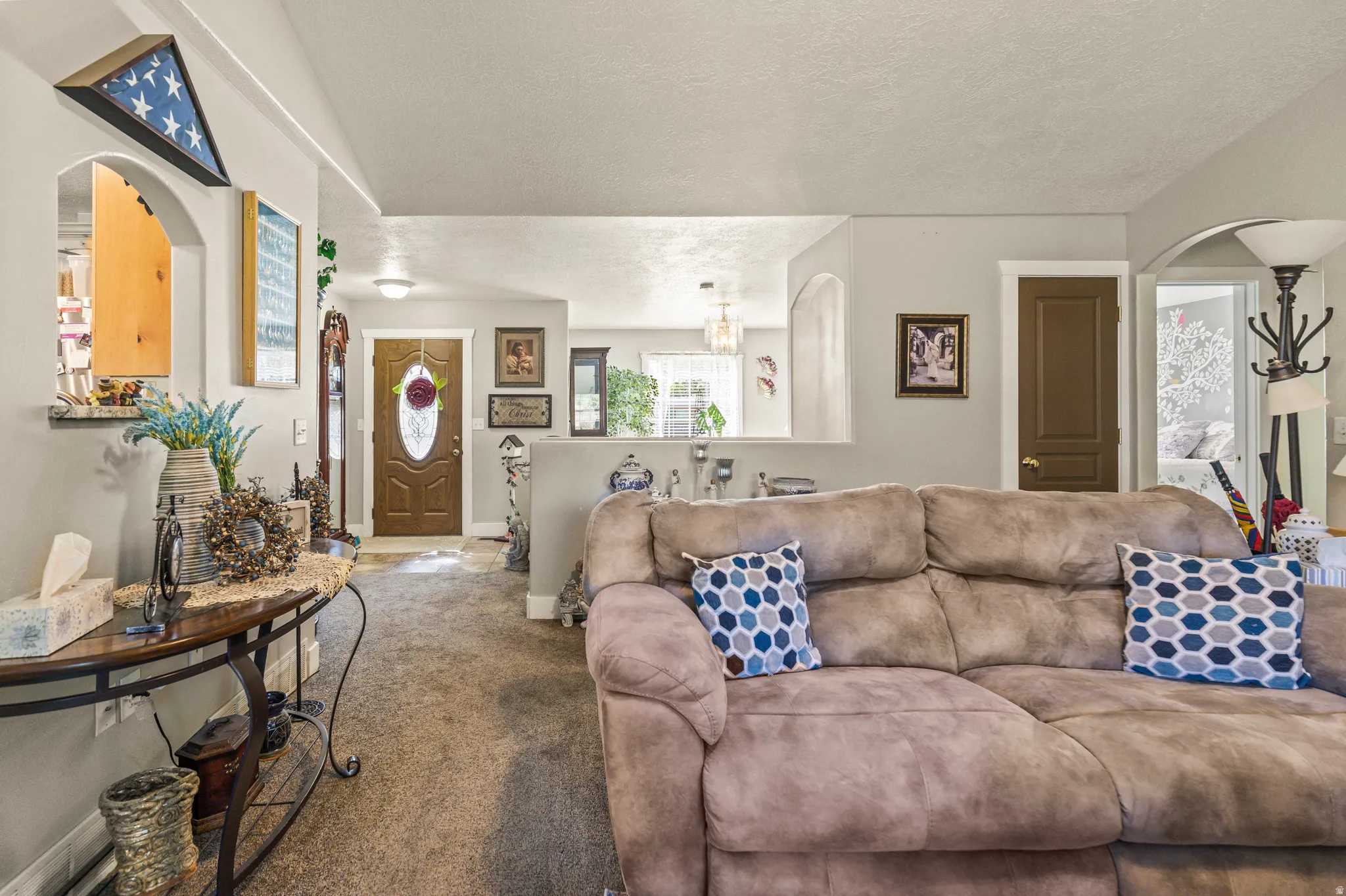 Archway entryways, wood-finish front door, overhead lighting, and carpet flooring
