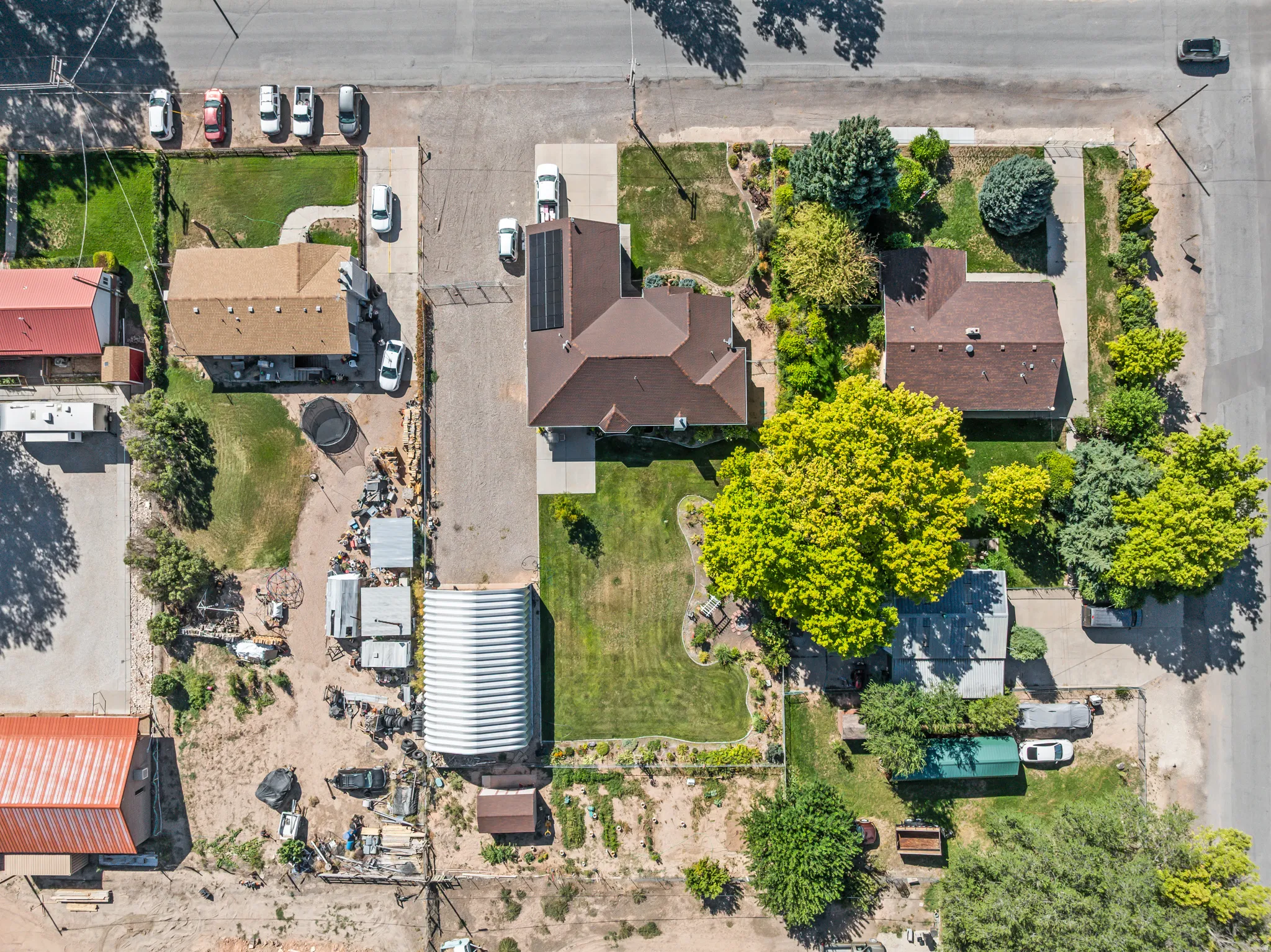 Expansive property with multiple buildings, mature trees, and paved parking areas