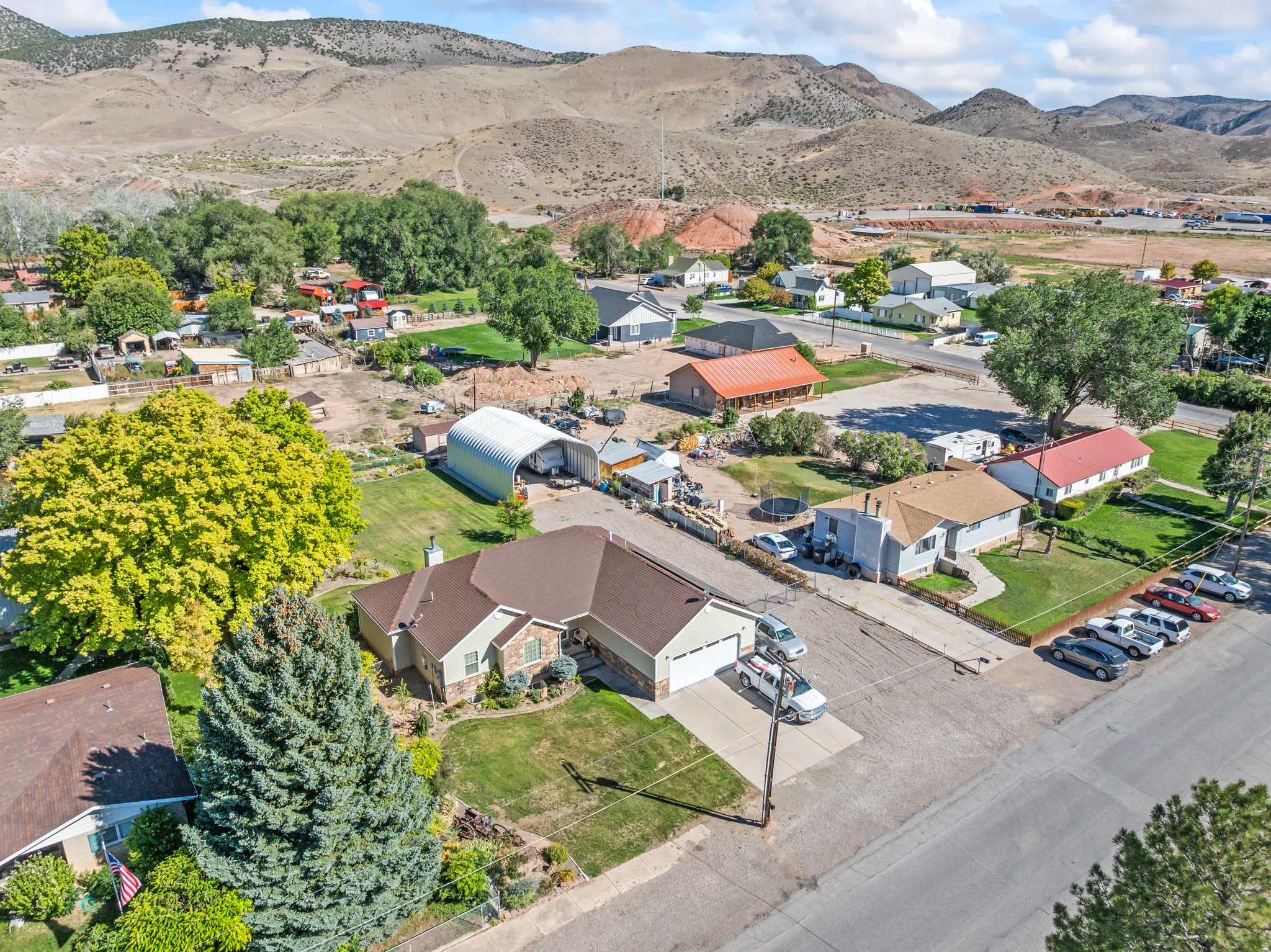 Expansive property featuring a detached metal Quonset hut, two-car garage, and a large front yard with mature landscaping
