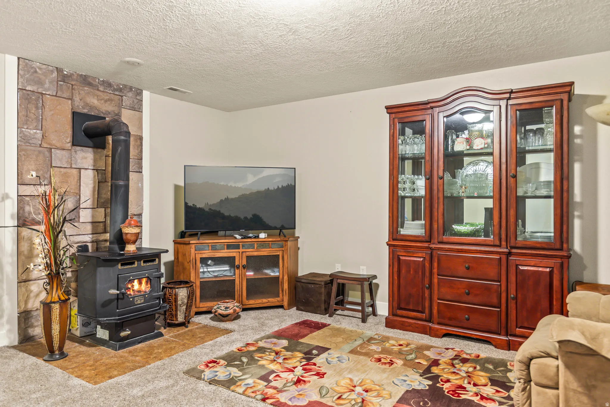 Stone accent wall with a wood-burning stove and a stone tile hearth