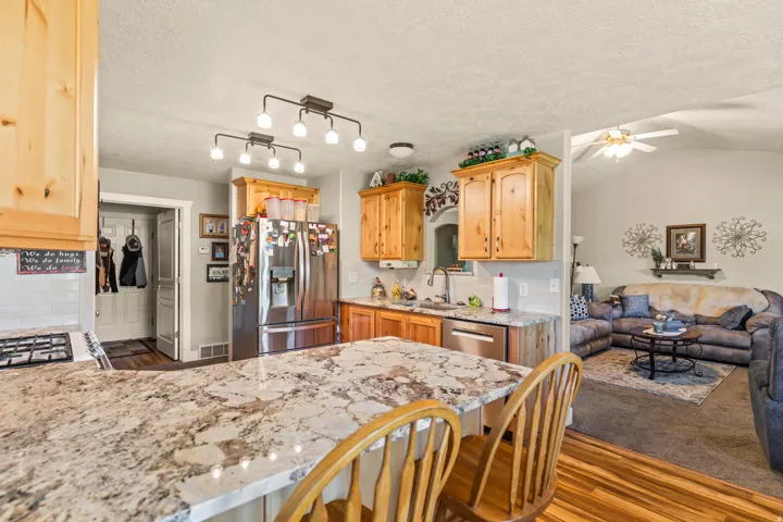 Kitchen featuring wood cabinetry, stainless steel appliances, and a breakfast bar with stone-look countertop