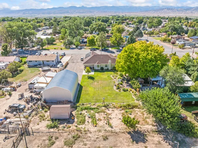 Expansive property featuring a large quonset hut, a manicured lawn, established landscaping, and a garden area