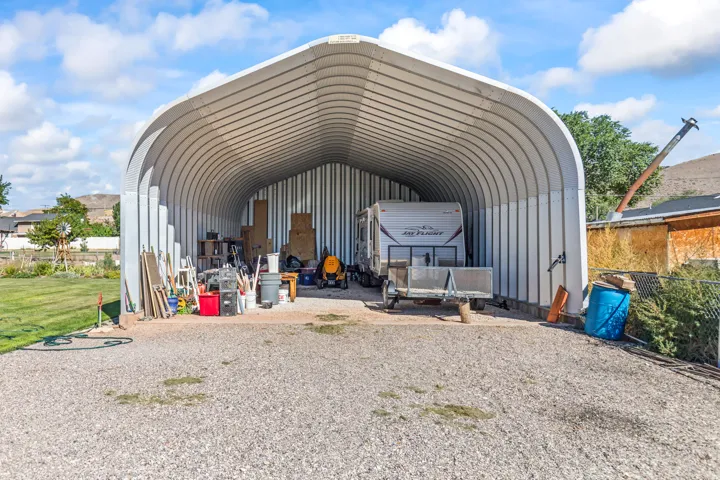 Quonset hut style structure with a corrugated metal roof and side panels, featuring a gravel floor