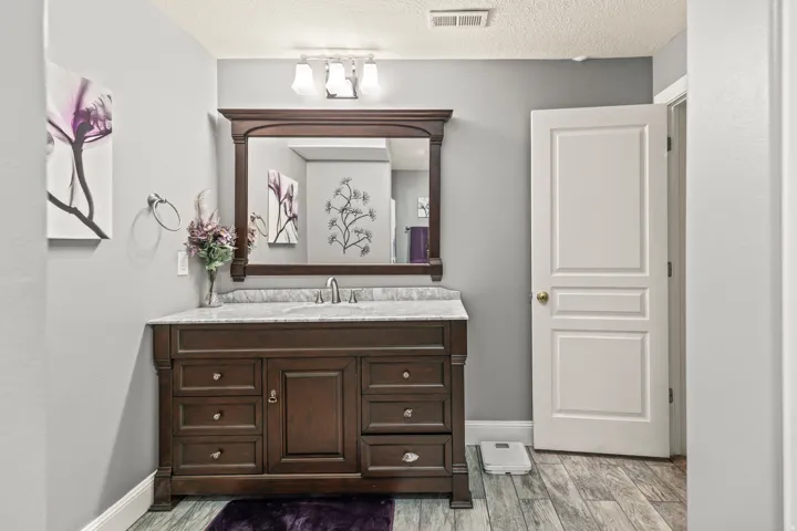 Dark wood-finish vanity with ample storage, integrated sink, and stone countertop
