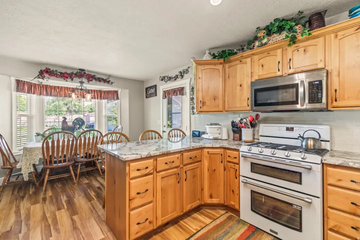 Kitchen featuring wood-finish flooring, light wood cabinetry, white subway tile backsplash, and light-toned countertops