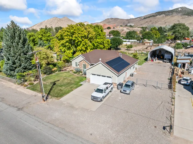 Single-story residence featuring a two-car garage, solar panels, and a stone facade accent