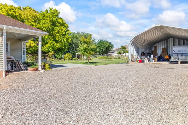Expansive gravel driveway with a detached metal quonset hut structure