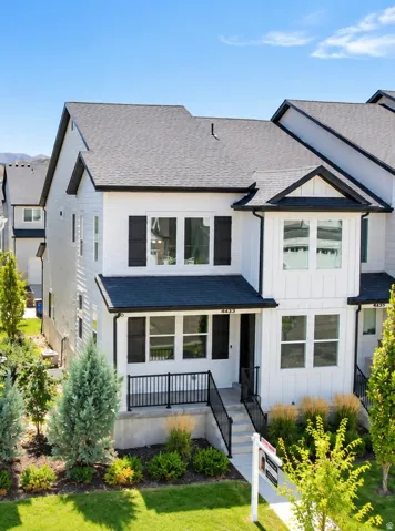 Modern exterior featuring white siding, dark shutters, a dark roof, and a front porch with black railings