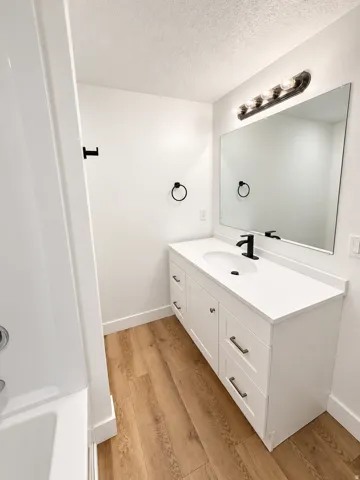 White vanity with shaker-style cabinetry, a white countertop, and an undermount sink