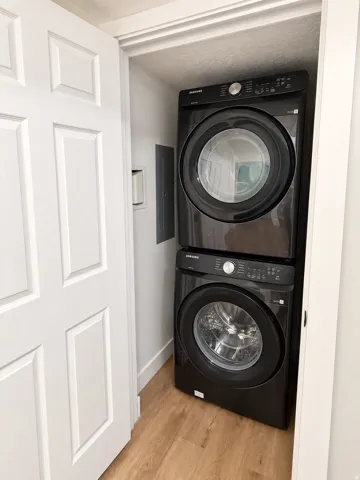 Stacked laundry appliances with wood-finish flooring