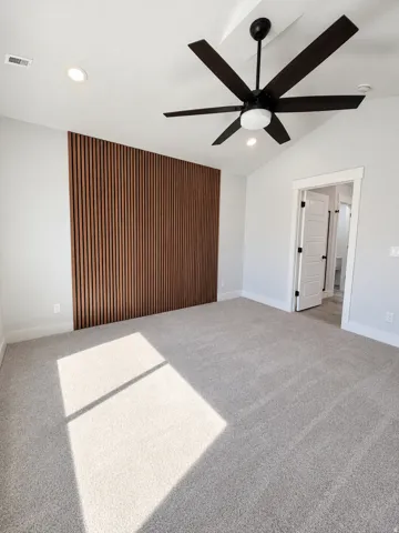 Vaulted ceiling with a contemporary ceiling fan, recessed lighting, and a textured accent wall