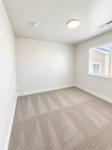 Carpeted room with a flush-mount ceiling light and a window with horizontal blinds