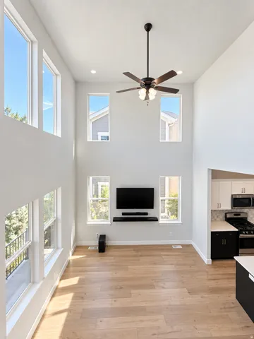 Two-story volume ceiling, wood-finish flooring, recessed lighting, ceiling fan, and multiple windows