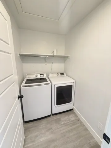 Dedicated laundry space featuring wood-finish flooring and an integrated storage shelf