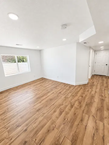 Recessed lighting, wood-finish flooring, white walls, and a white paneled door