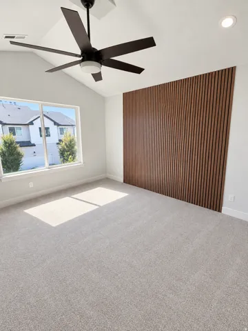 Vaulted ceiling with a dark-bladed ceiling fan and integrated lighting
