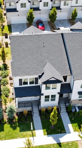 Contemporary townhome architecture with dark shingle roofing, white siding, and black trim