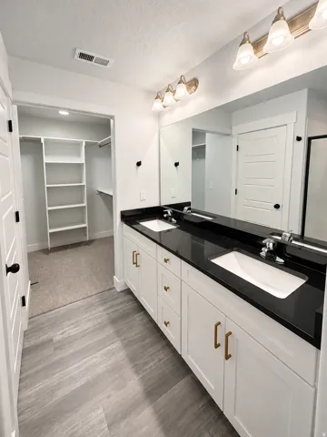 Double vanity with white cabinetry, black countertops, and dual undermount sinks