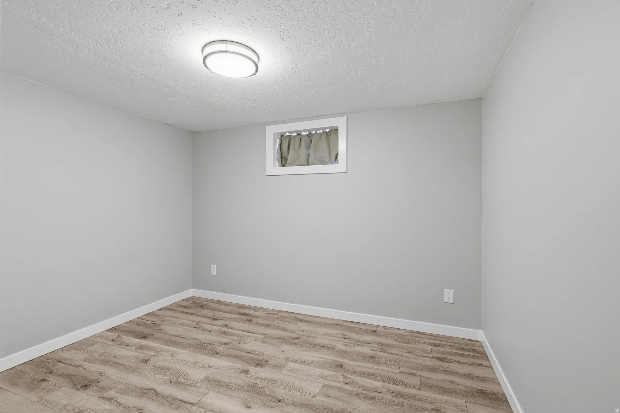 Lower level bedroom with laminate flooring and fresh neutral paint.