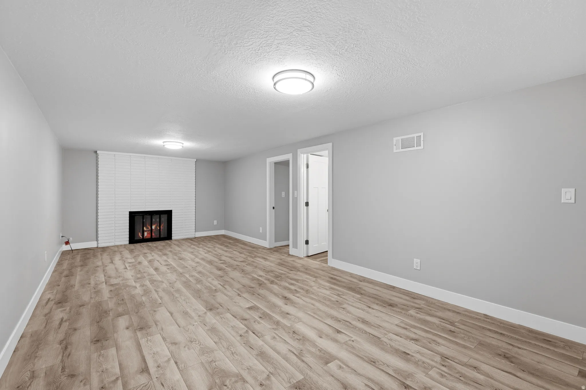 Lower level gathering space with fireplace, laminate flooring, fresh neutral paint and LED lighting