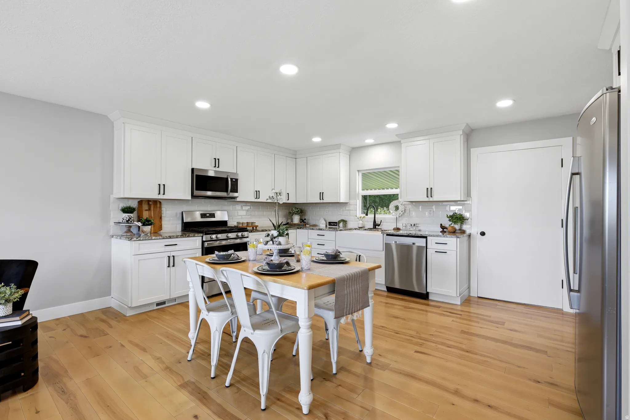 Farmhouse white kitchen with included refrigerator, hardwood floors and granite countertops
