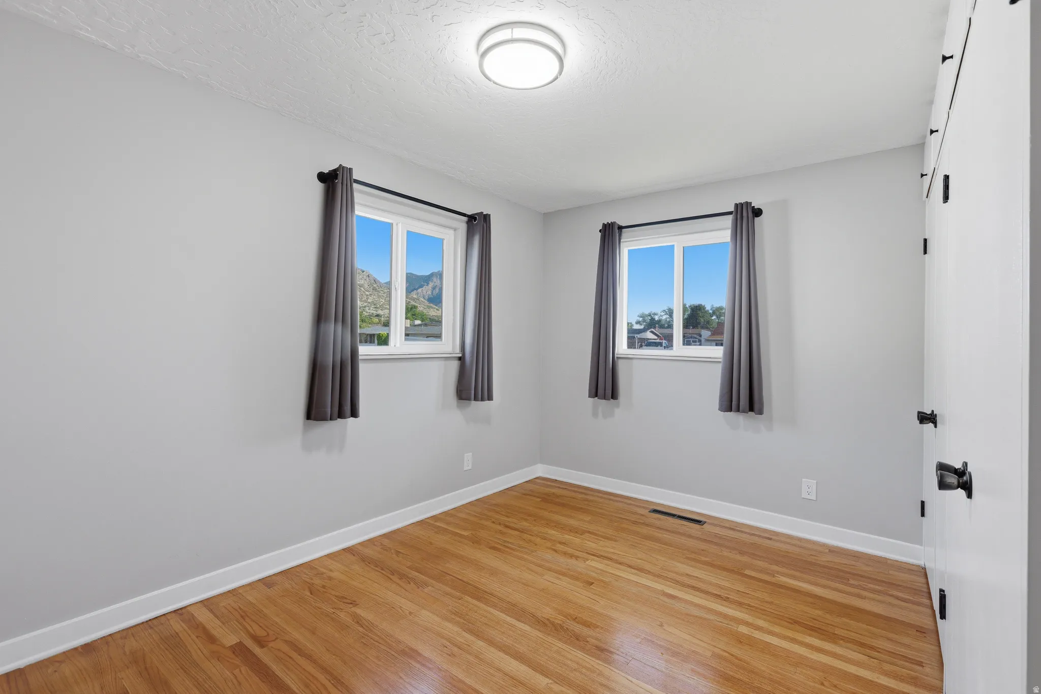 Main floor bedroom with double updated windows, hardwood flooring and fresh neutral paint